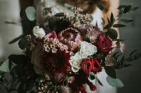 a textural winter wedding bouquet with foliage, red blooms, cascading amaranthus and dahlias