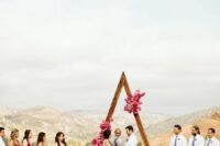 a triangle wedding arch covered with bougainvillea and some greenery is a lovely idea for a bright boho wedding in summer