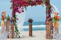 a tropical wedding arch covered with bougainvillea, greenery and bold tropical blooms and greenery for a beach wedding