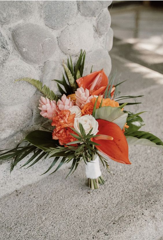 a tropical wedding bouquet of blush and orange blooms, anthurium and greenery is a cool idea for a wedding