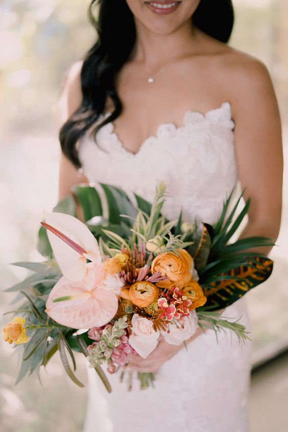 a tropical wedding bouquet of blush roses, anthurium, yellow ranunculus, greenery and foliage is a catchy and lovely idea