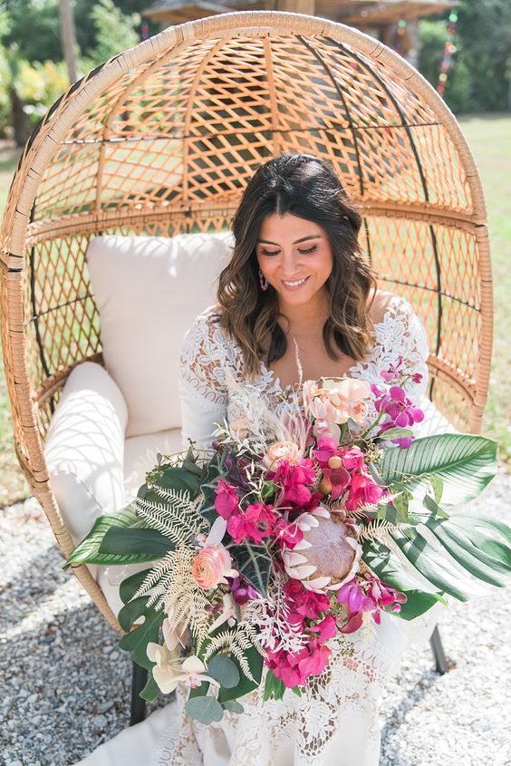 a tropical wedding bouquet with peachy ranunculus, bougainvillea, blush fillers, fronds and dried leaves plus king proteas
