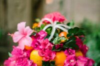 a tropical wedding centerpiece of bougainvillea, greenery, citrus and air plants is an amazing idea for a colorful wedding