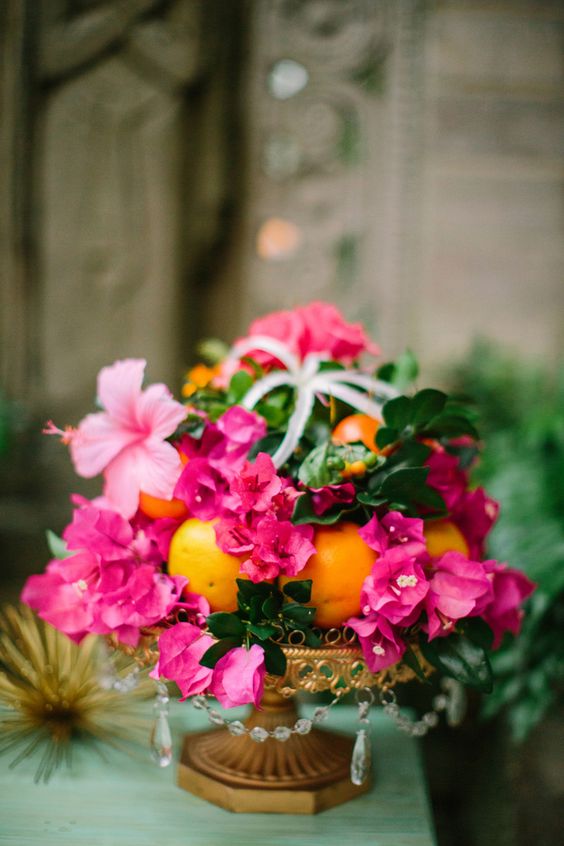 a tropical wedding centerpiece of bougainvillea, greenery, citrus and air plants is an amazing idea for a colorful wedding