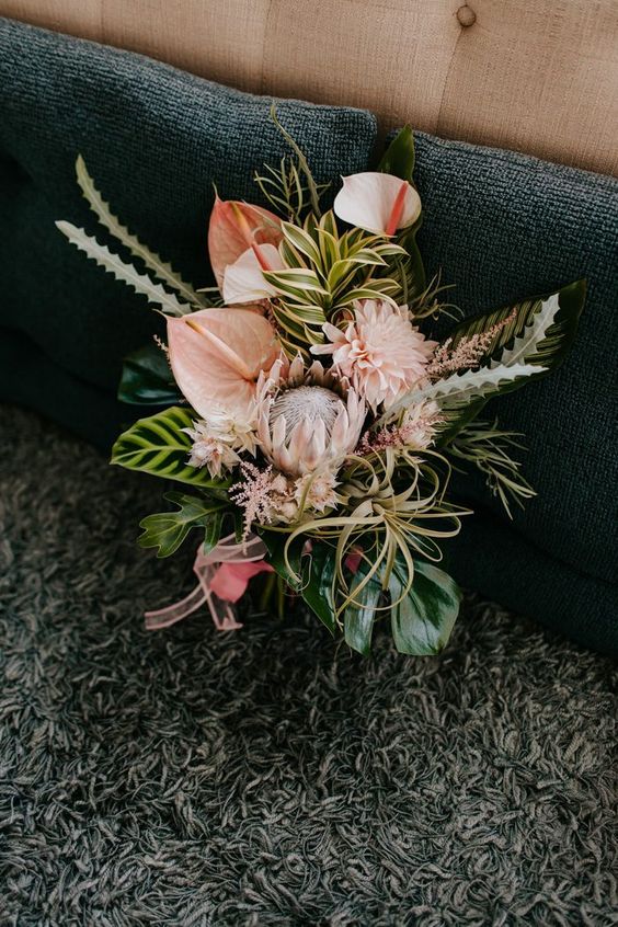a unique wedding bouquet of blush and white anthurium, king proteas, dahlias, greenery and air plants