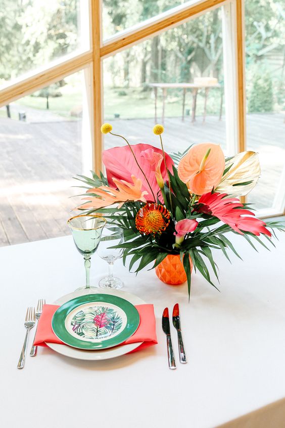a vibrant tropical wedding centerpiece of anthuriums, callas and proteas, billy balls and large fronds is wow