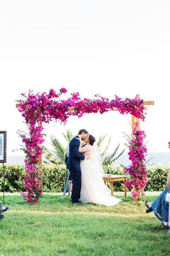 a vibrant wedding arch covered with only bougainvillea is a cool idea that always works if you love this color