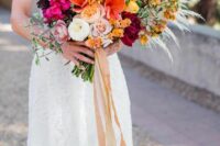 a vibrant wedding bouquet of neutral peony roses, peachy ranunculus, orange blooms, greenery, pampas grass and bougainvillea