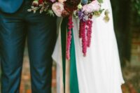 a vibrant wedding bouquet of pink and red blooms, deep burgundy dahlias and mums, greenery and amaranthus for the fall