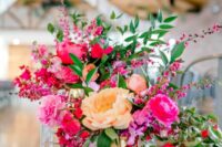 a vibrant wedding centerpiece of hot and light pink peonies, yellow and blush ones, greenery and bougainvillea is amazing for summer