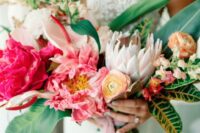 a vivacious wedding bouquet of coral peonues, yellow ranunculus, anthurium, greenery and leaves is amazing for a tropical bride