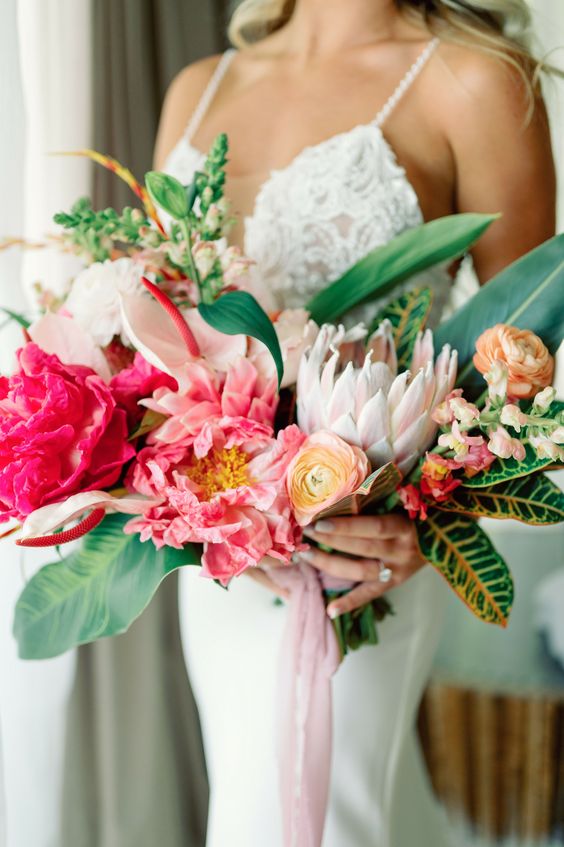 a vivacious wedding bouquet of coral peonues, yellow ranunculus, anthurium, greenery and leaves is amazing for a tropical bride