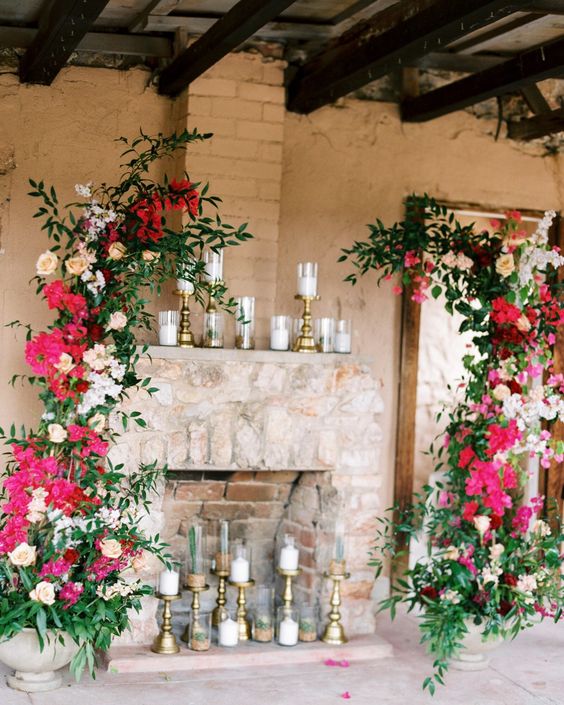 a wedding altar of greenery, peachy roses and white hydrangeas, bougainvillea and candles in the fireplace and on the mantel