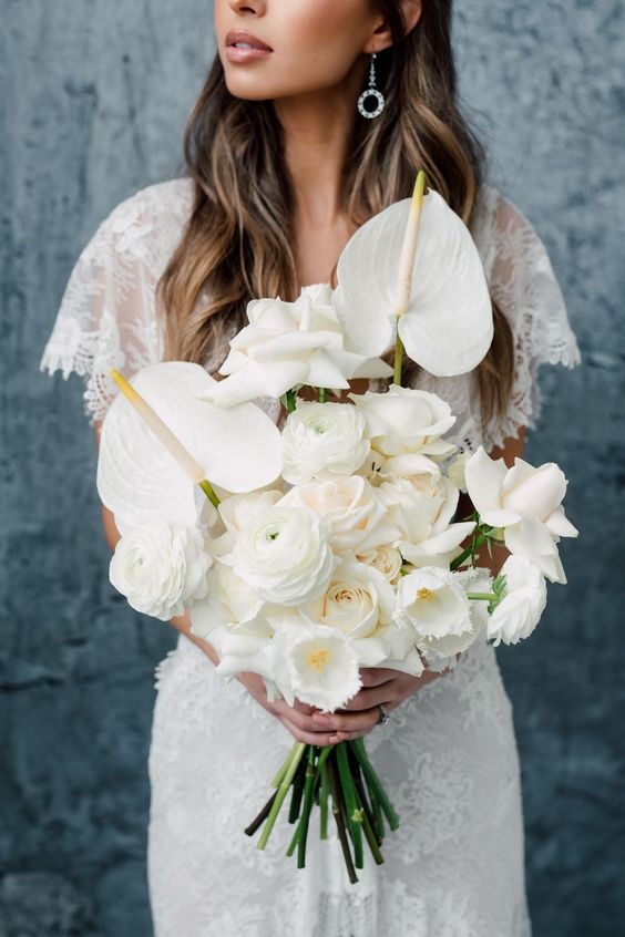 a white wedding bouquet of anthurium, roses and ranunculus is a stylish and lush solution for a modern bride