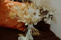 a white wedding bouquet of lunaria and some dried grasses plus white ribbon is a truly boho wedding bouquet in neutrals