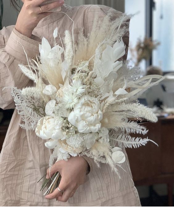 a white wedding bouquet of peonies, lunaria, grasses and leaves plus bunny tails is a chic and cool idea with many dried elements