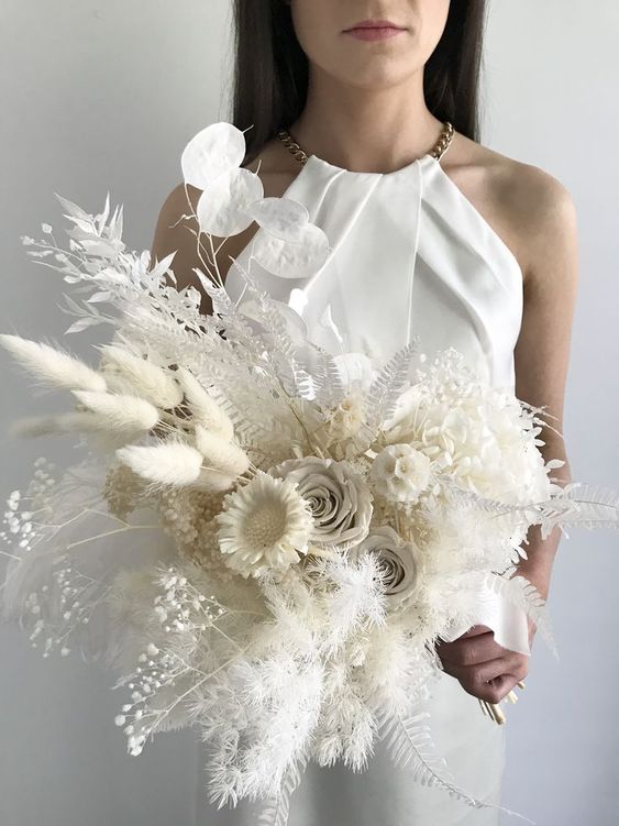 a white wedding bouquet of roses, seed pods, dried leaves and grasses, lunaria and baby's breath is a chic and cool solution