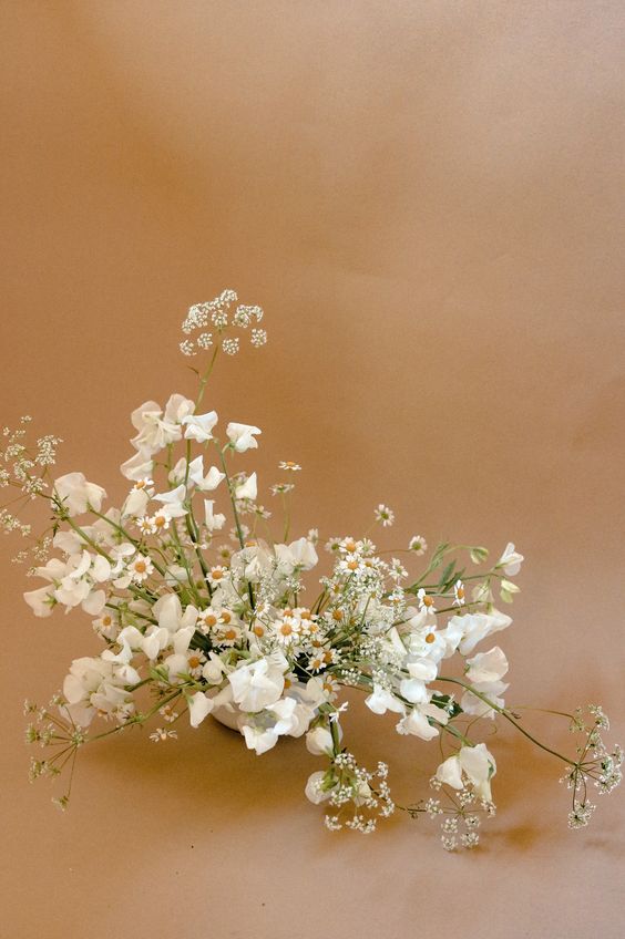 a white wedding centerpiece of chamomiles and sweet peas is a lovely idea for a spring or summer wedding