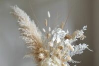 a white wedding centerpiece of hydrangeas, pampas grass, dried blooms and grasses, lunaria and bunny tails is adorable
