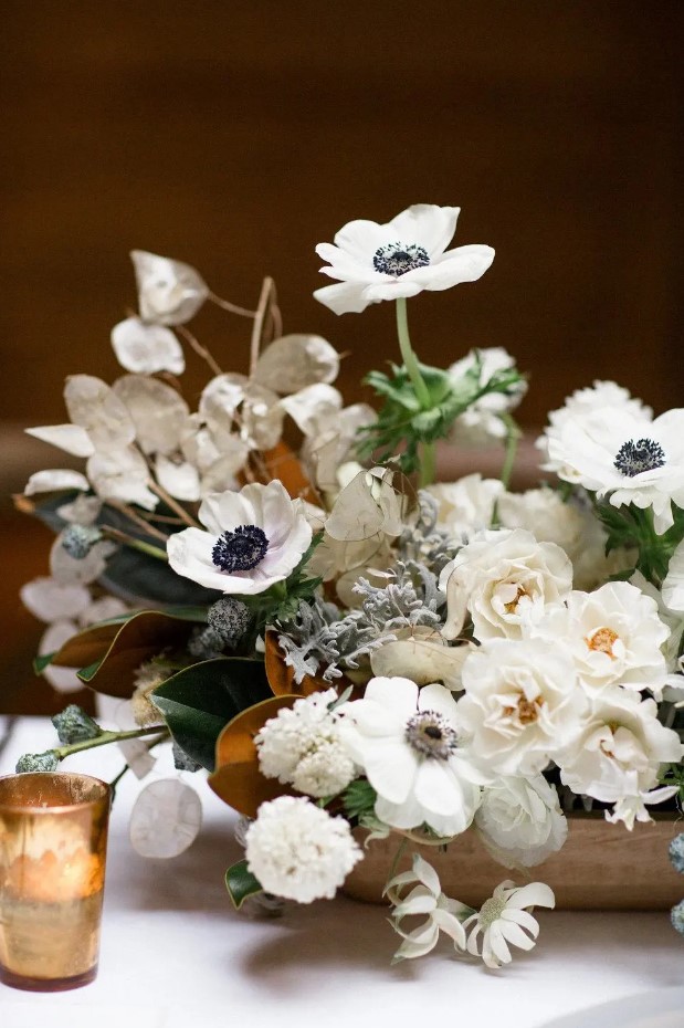 a white wedding centerpiece of roses, anemones, mums and lunaria plus magnolia leaves and pale miller is adorable