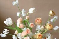 an airy spring wedding centerpiece of white sweet peas, blush peony roses and yellow ranunculus and greenery is adorable