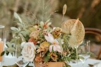 an earthy wedding centerpiece of blush and rust blooms, greenery, grasses and anthurims is a lovely idea for a boho wedding
