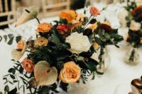 an elegant wedding centerpiece of white and yellow roses and carnations, greenery, berries and anthurium for a chic wedding