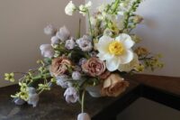 an exquisite wedding centerpiece of lilac tulips, coffee-colored roses, white blooms and greenery for spring or summer