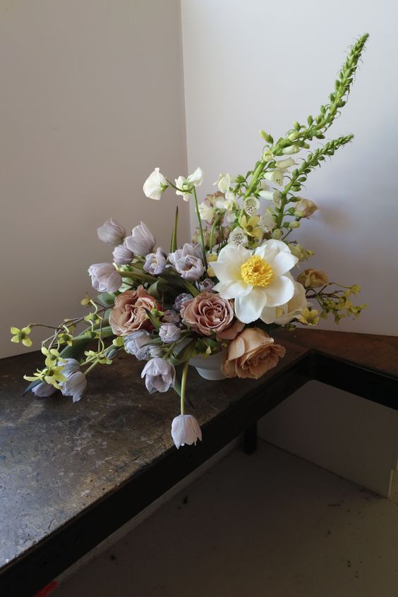 an exquisite wedding centerpiece of lilac tulips, coffee-colored roses, white blooms and greenery for spring or summer