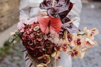 an extra bold wedding bouquet of burgundy and coral anthurium, peachy orchids and burgundy hydrangeas is wow