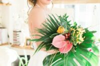 an oversized wedding bouquet with pink and yellow blooms and oversized tropical leaves