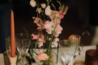 an ultra-modern wedding centerpiece of pink and peachy sweet peas and bunny tails ina  terracotta pot and some pink ranunculus