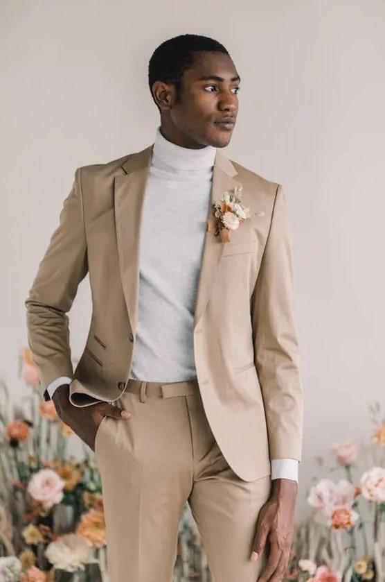 a cool minimalist groom's look with a tan pantsuit, a neutral turtleneck and a dried flower boutonniere is pure perfection