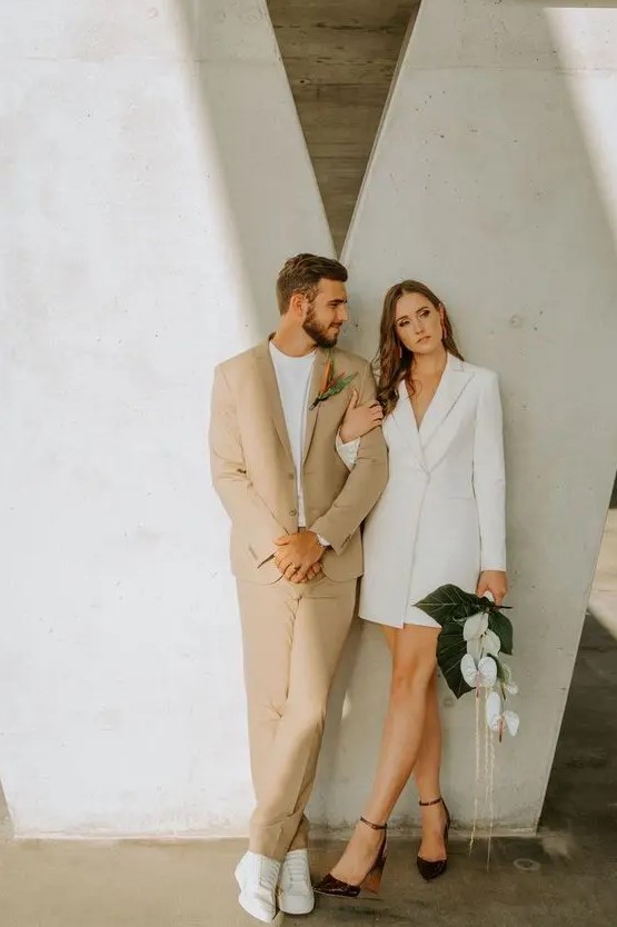 a minimalist groom's outfit with a tan pantsuit, a white t-shirt and white sneakers is effortlessly chic and cool