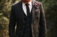 17 a brown plaid three-piece suite with a brown tie and a white shirt, a taupe handkerchief and a bold floral boutonniere