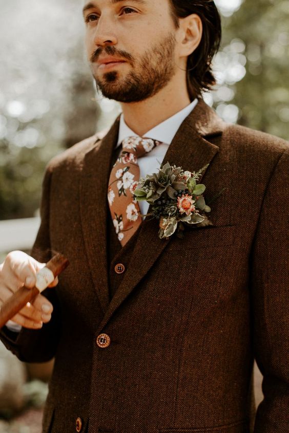a brown three-piece pantsuit, a white shirt, an orange floral tie, a floral boutonniere are a cool combo for a boho groom