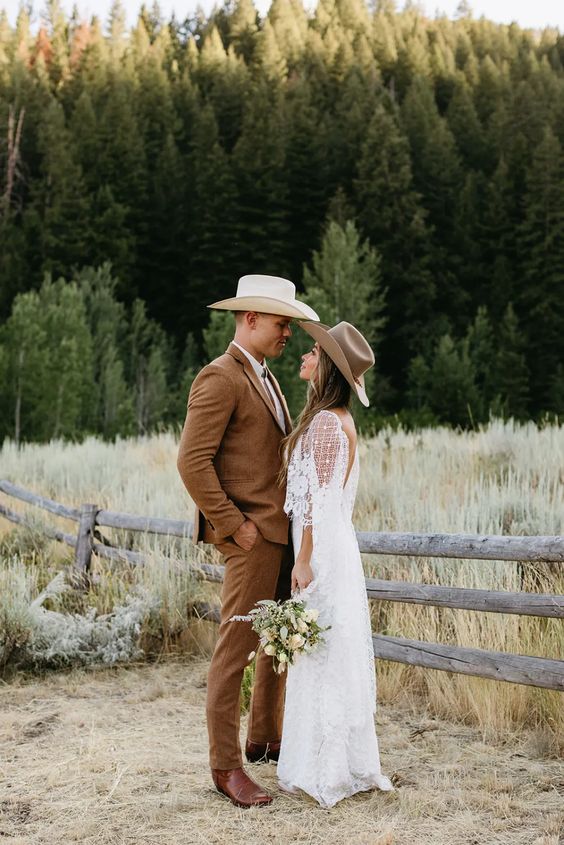 a cowboy groom's outfit with a brown pantsuit, brown boots, a hat and a bolo tie is cool for a rustic wedding