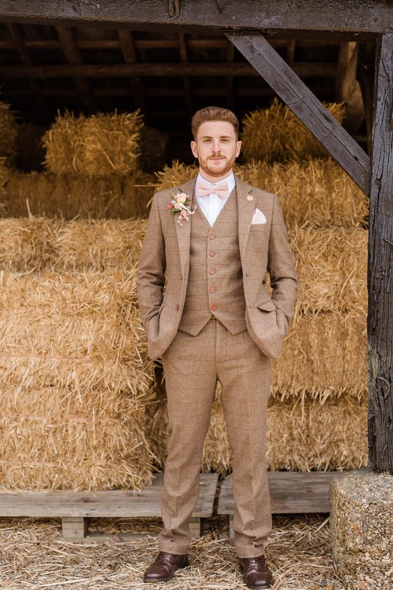 a light brown three-piece checked pantsuit, a white shirt, a pink bow tie and black shoes for a rustic groom's look