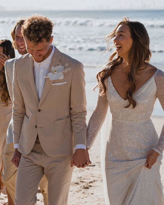 a tan pantsuit, a white shirt, a white orchid boutonniere are a great combo for a beach groom's look