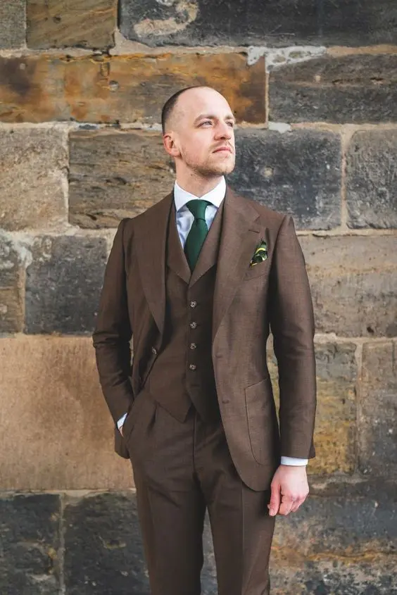 a stylish brown three-piece pantsuit, a white shirt, a green tie and a handkerchief are a cool combo for a chic wedding