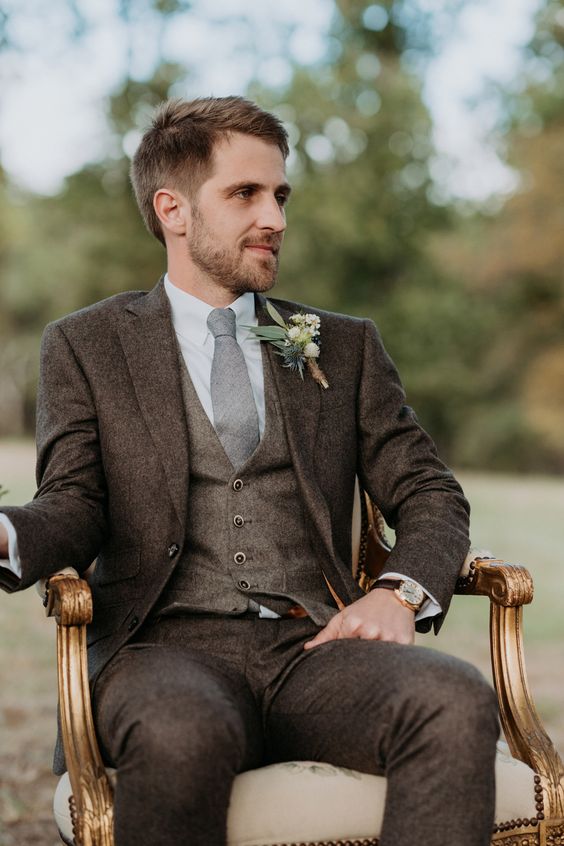 a stylish groom's look with a brown three-piece pantsuit, a white shirt, a grey tie and a boutonniere is amazing for the fall