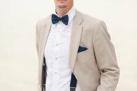 40 an elegant coastal groom’s look with a tan pantsuit, a white shirt, a navy bow tie and suspenders, a navy handkerchief