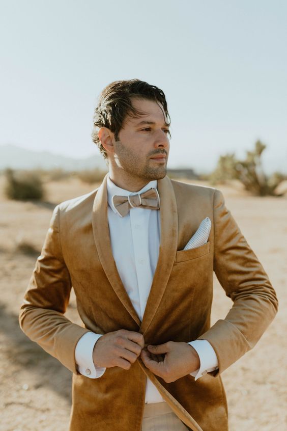 a beige velvet blazer, a tan bow tie and a white shirt are a cool look for a boho wedding in summer or fall