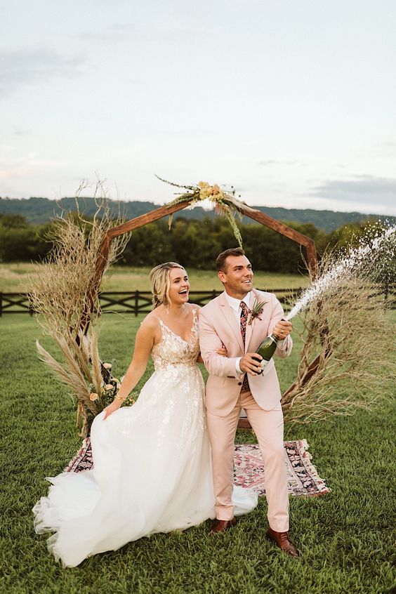 a blush pantsuit, a white shirt, a floral tie and brown shoes are a great combo for a boho wedding