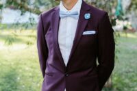a bold groom’s outfit with a purple blazer, a white shirt, a light blue bow tie and handkerchief, neutral pants