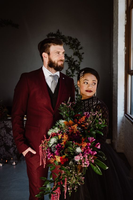 a bold modern groom's look with a burgundy pantsuit, a black waistcoat, a grey tie and a white shirt