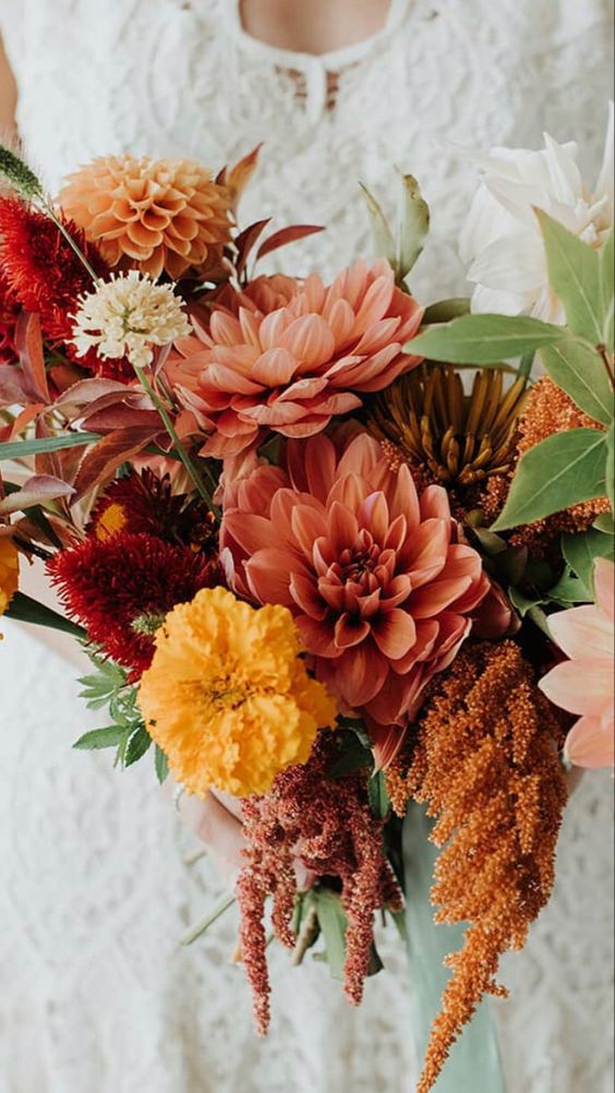 a bright fall wedding bouquet of marigolds, dahlias, chrysanthemums, amaranthus and greenery in truly fall shades