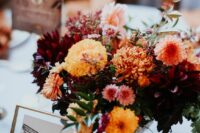 a bright fall wedding centerpiece of yellow, coral, burgundy, orange blooms including mums and some greenery