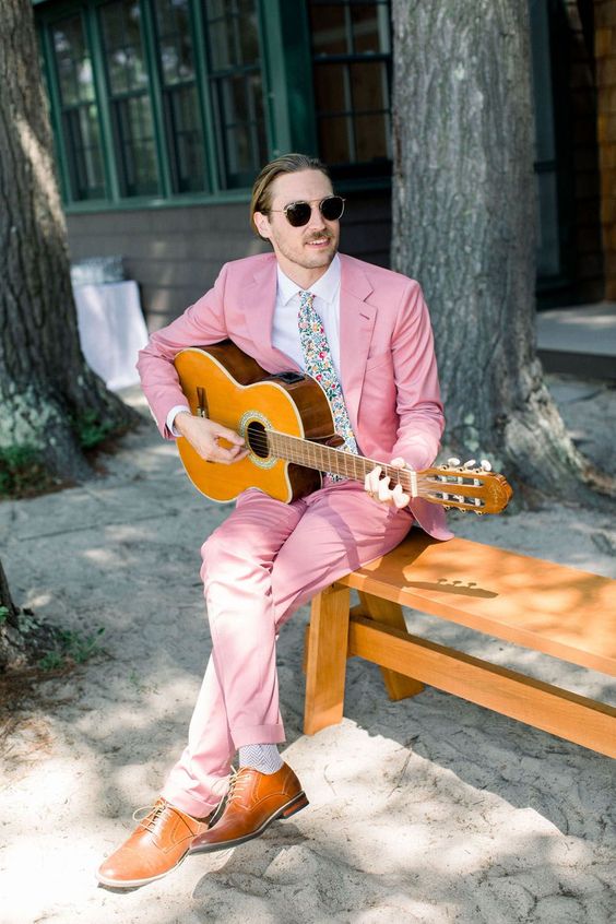 a bright groom's look with a bright pink pantsuit, a white shirt, a colorful tie, amber shoes is a cool solution for a boho wedding