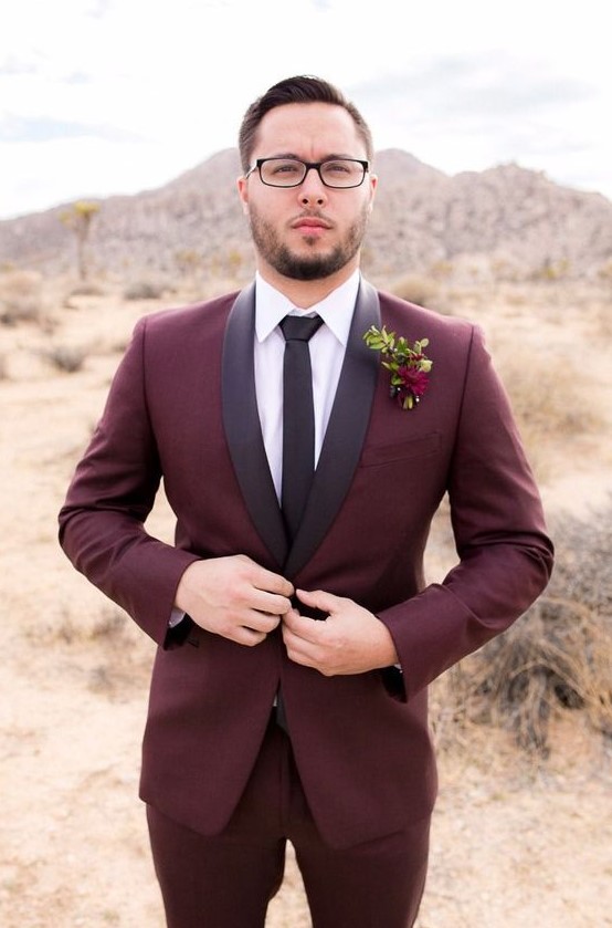 a burgundy tuxedo with black lapels, a white shirt and a black tie plus a bold floral boutonniere for a fall groom